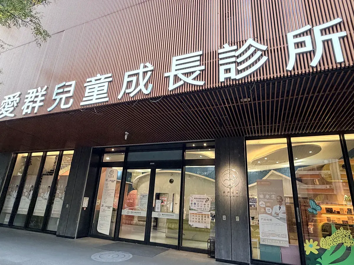 愛群兒童成長診所外觀，上方招牌寫著愛群兒童成長診所，招牌下方是玻璃大門